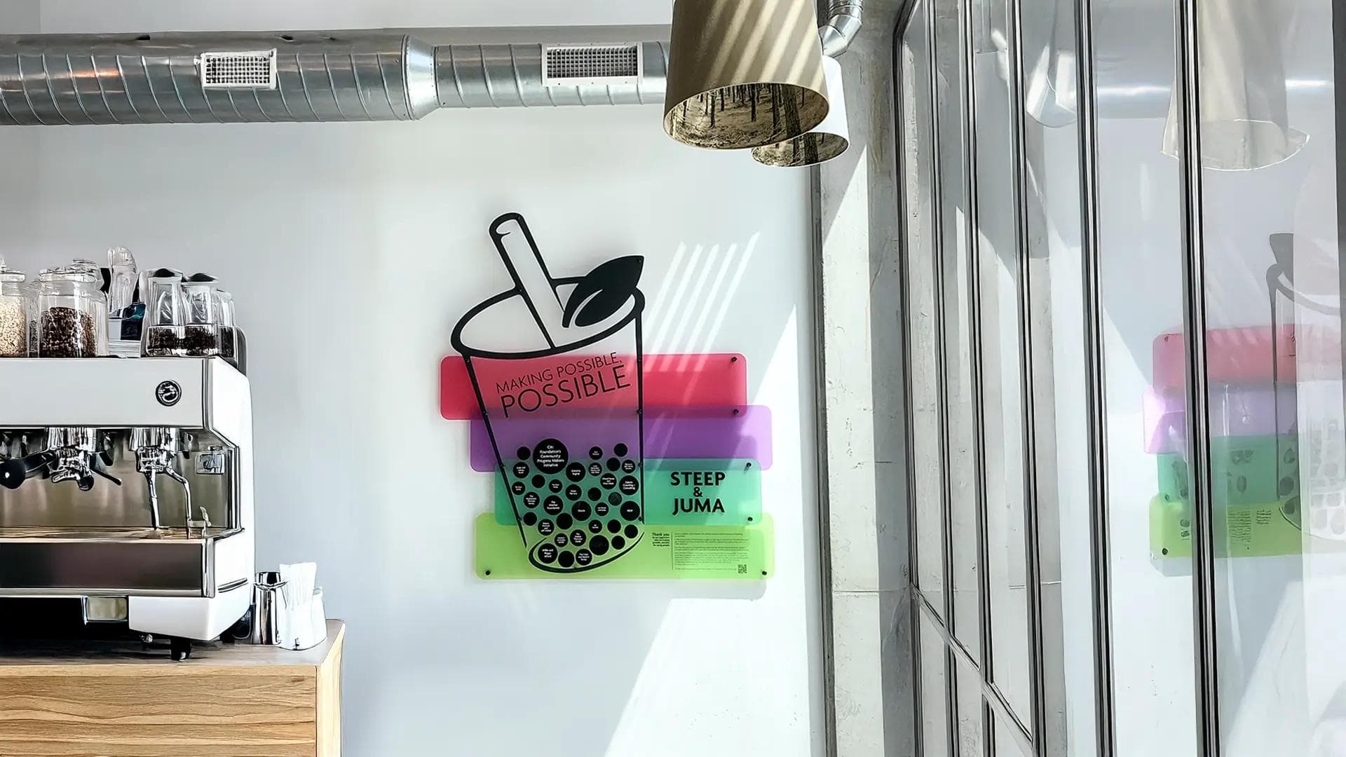 Colorful acrylic donor recognition wall with bubble tea graphic and layered panels inside a modern café space.