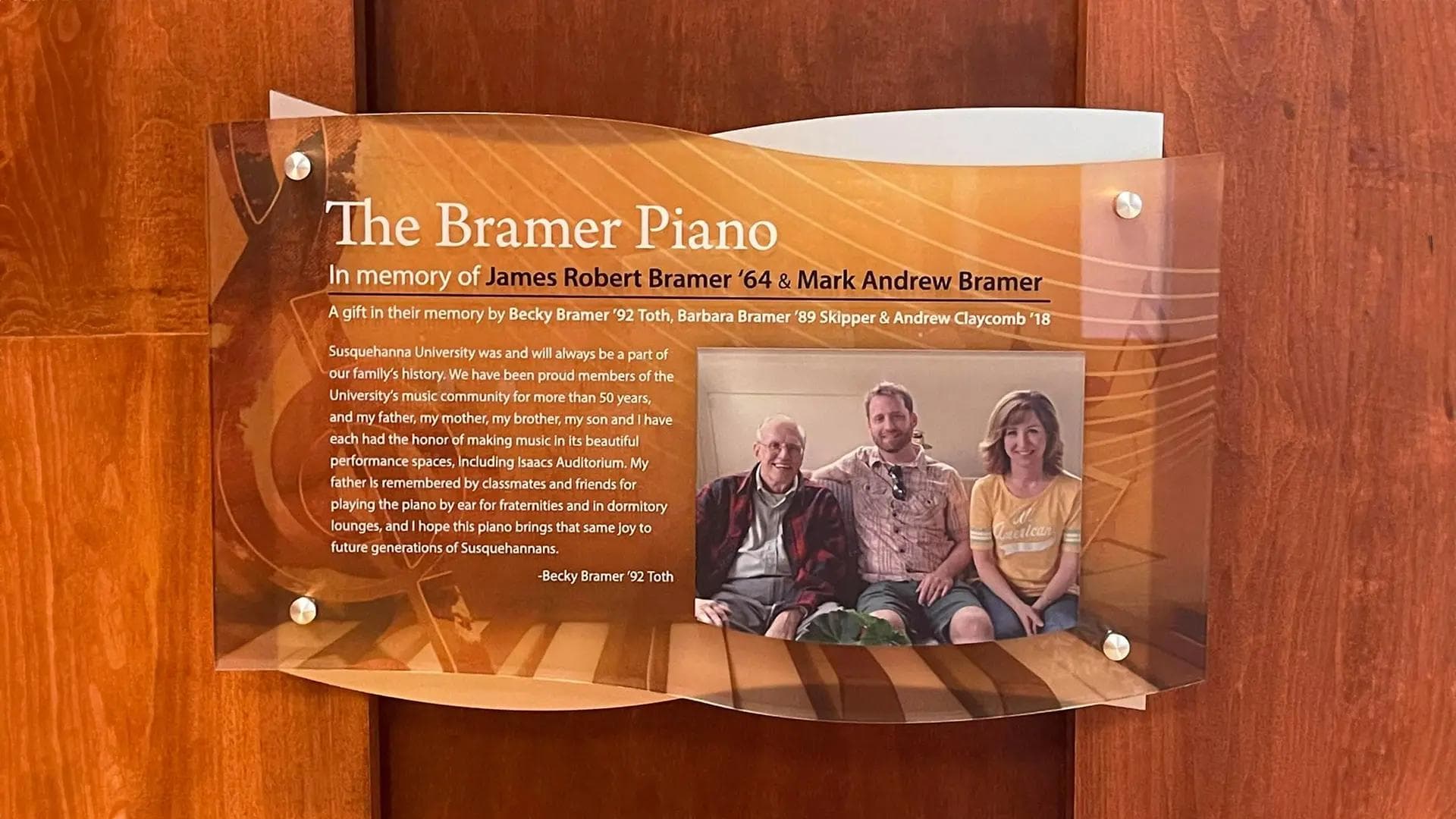 Susquehanna University donor plaque honoring the Bramer Piano with layered acrylic, printed music graphics, and family photo.
