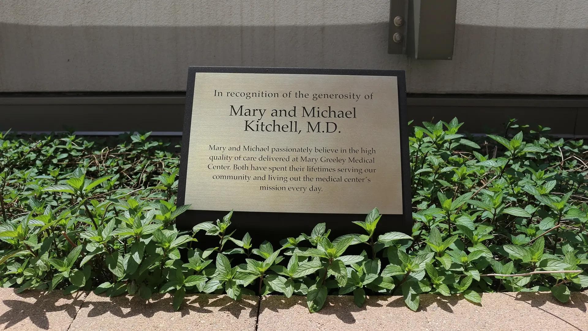 Outdoor donor recognition plaque at Mary Greeley Medical Center set within landscaped greenery honoring philanthropic support.